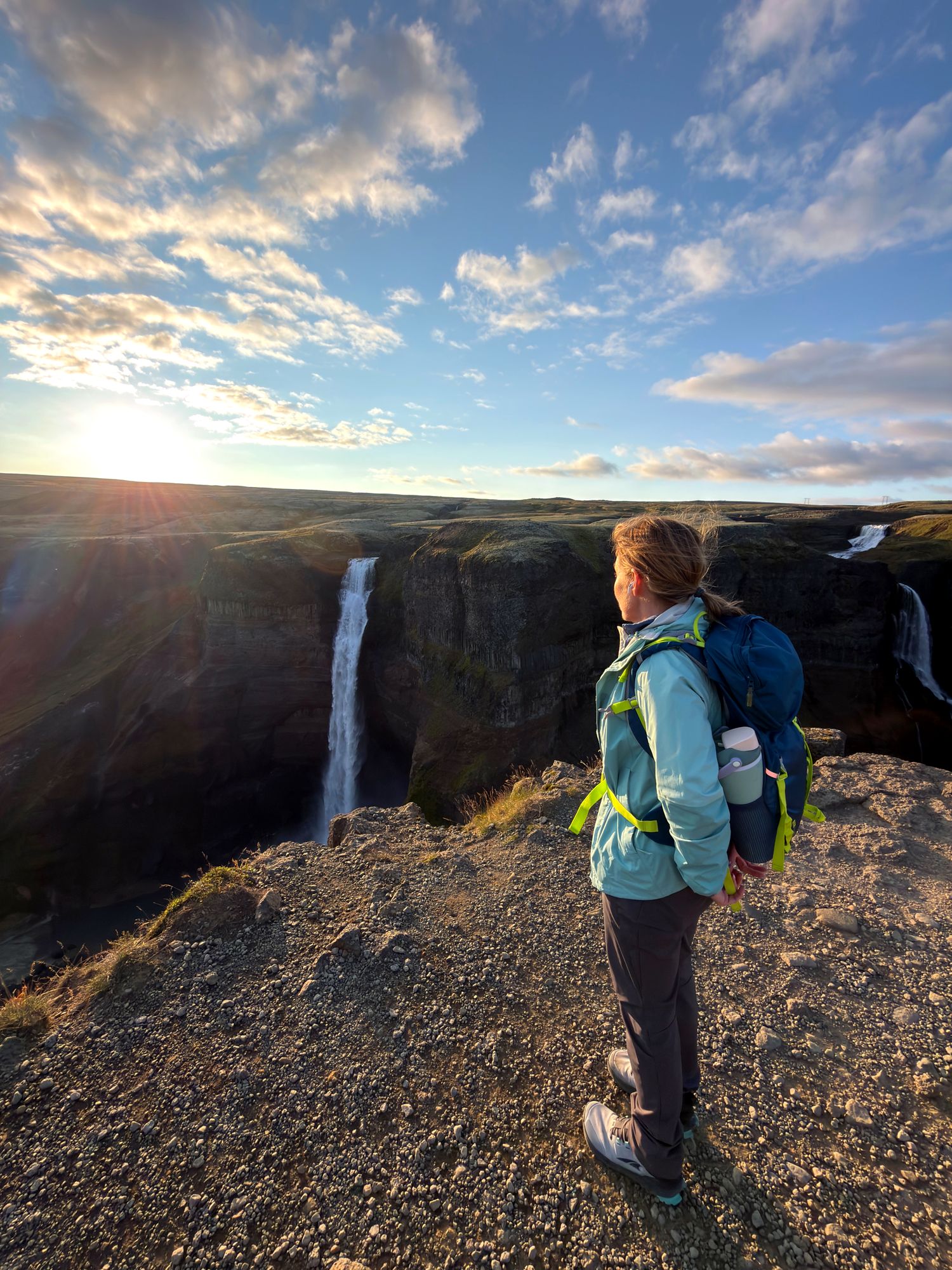 Jeanne standing at the rim of a canyon at sunset, looking out at Háifoss waterfall in Iceland