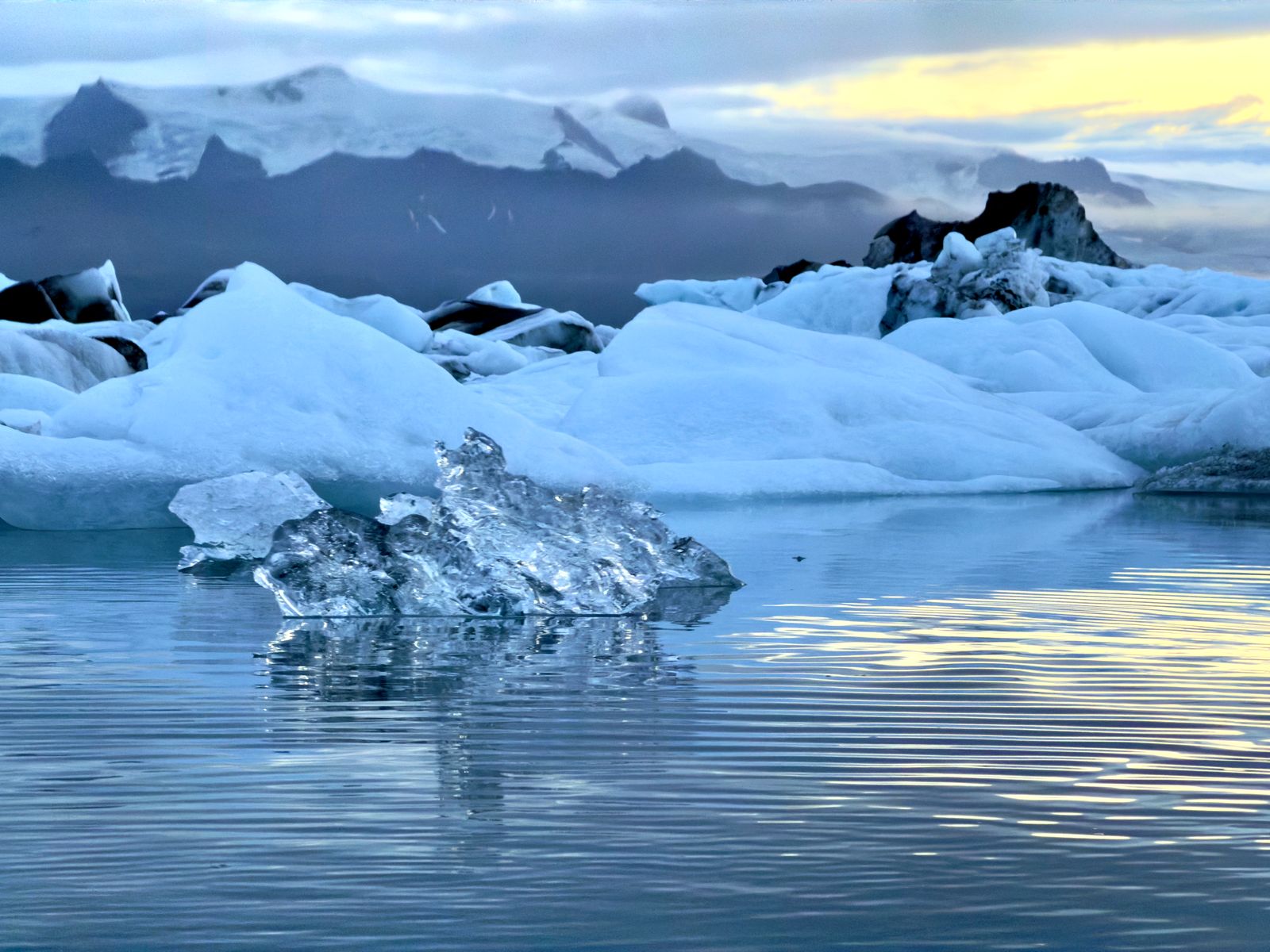 Icebergs in a glacier lagoon with snow-covered mountains behind