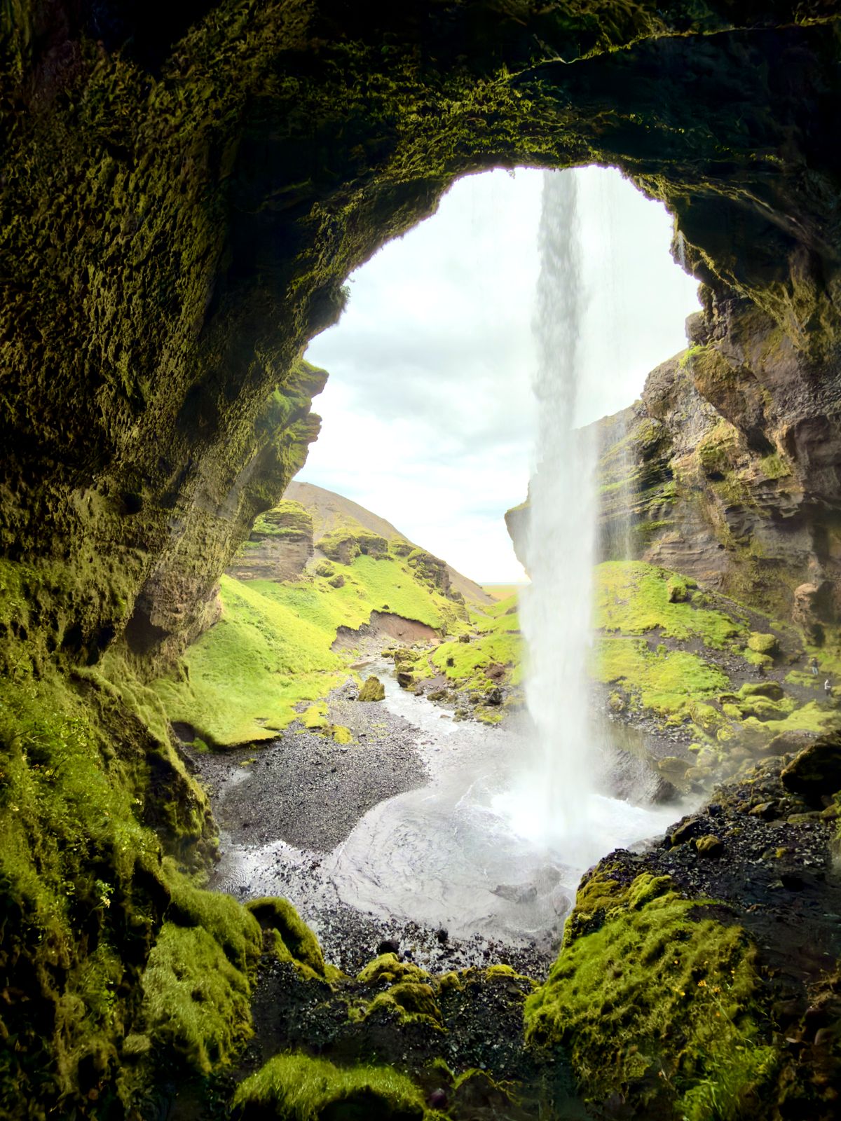 A waterfall seen from inside a mossy cave